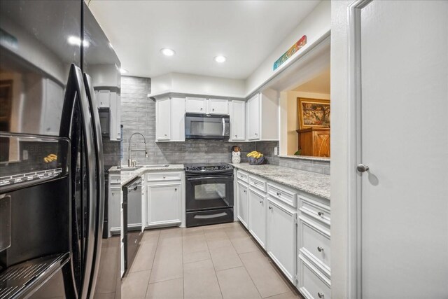 kitchen featuring sink, white cabinetry, light stone counters, tasteful backsplash, and black appliances