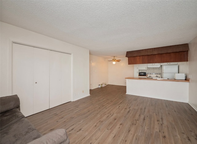 unfurnished living room with ceiling fan, hardwood / wood-style flooring, and a textured ceiling