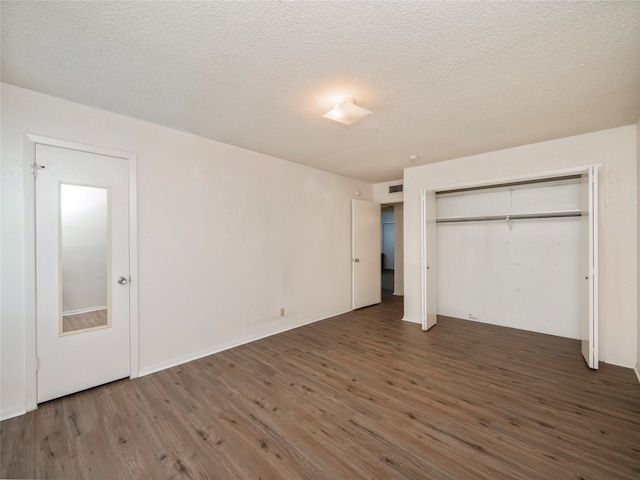 unfurnished bedroom featuring a textured ceiling, dark wood-type flooring, and a closet