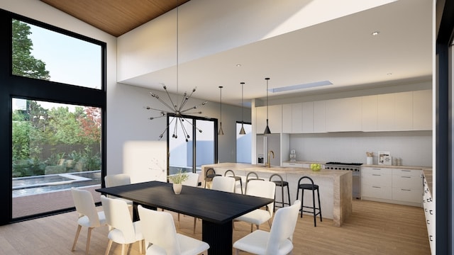 dining area with wood ceiling, a towering ceiling, sink, and light wood-type flooring