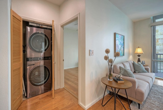 laundry area with light hardwood / wood-style flooring and stacked washer and dryer