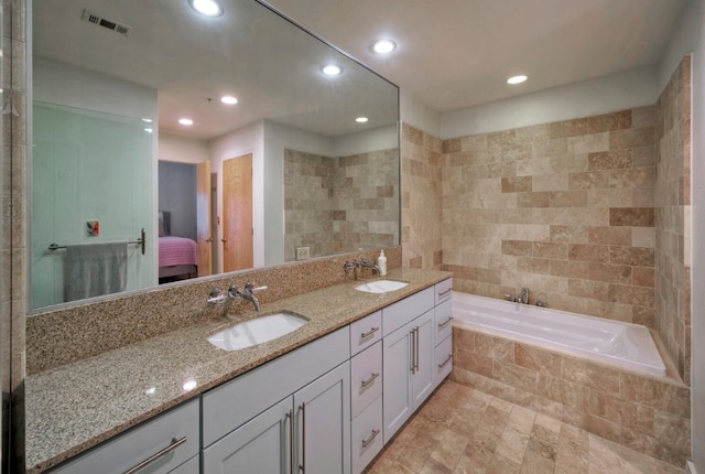 bathroom featuring tiled bath and vanity