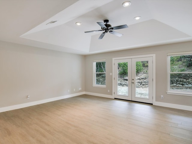 spare room featuring french doors, light wood-type flooring, a tray ceiling, and ceiling fan