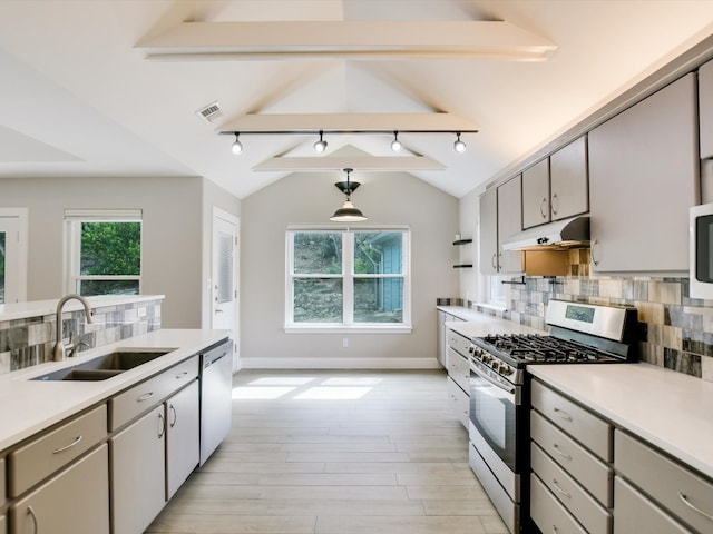 kitchen featuring appliances with stainless steel finishes, backsplash, sink, lofted ceiling with beams, and decorative light fixtures