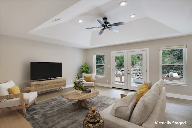 living room featuring ceiling fan, wood-type flooring, french doors, and a tray ceiling