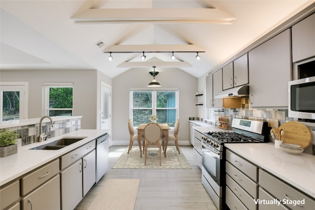 kitchen with sink, hanging light fixtures, tasteful backsplash, vaulted ceiling with beams, and appliances with stainless steel finishes