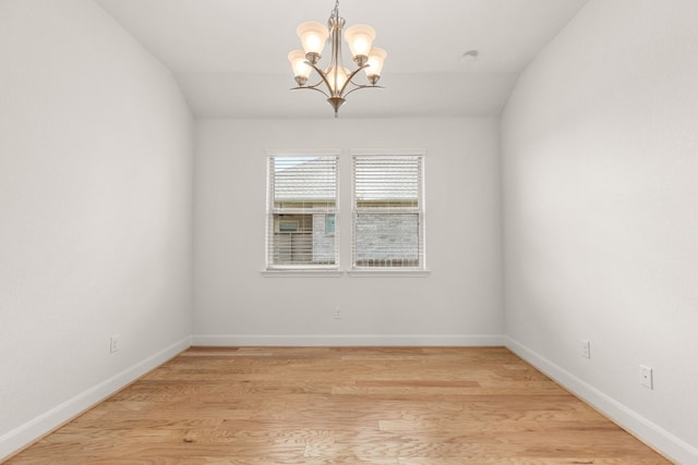 spare room with a chandelier, vaulted ceiling, and light hardwood / wood-style flooring