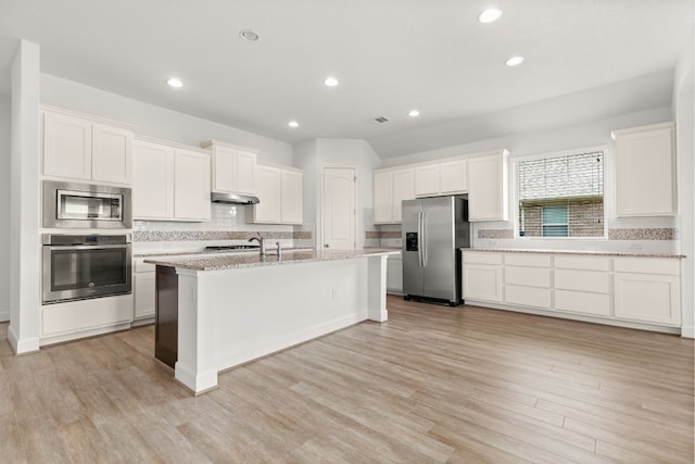 kitchen with white cabinets, appliances with stainless steel finishes, light hardwood / wood-style floors, and a center island with sink