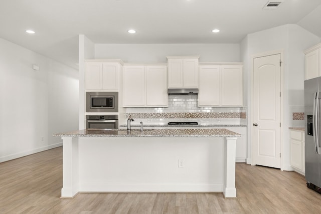 kitchen featuring decorative backsplash, appliances with stainless steel finishes, light wood-type flooring, white cabinetry, and an island with sink