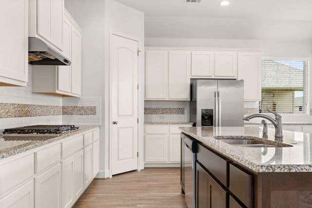 kitchen with appliances with stainless steel finishes, ventilation hood, sink, light hardwood / wood-style flooring, and white cabinets