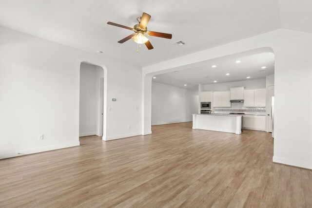 unfurnished living room featuring visible vents, light wood-style flooring, recessed lighting, arched walkways, and a ceiling fan