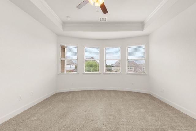 carpeted spare room featuring a raised ceiling, crown molding, and ceiling fan