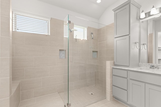 bathroom featuring tile patterned floors, vanity, lofted ceiling, and tiled shower