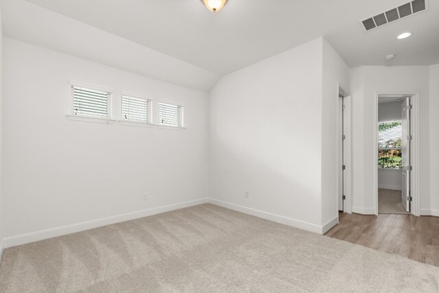 empty room featuring visible vents, lofted ceiling, recessed lighting, carpet floors, and baseboards