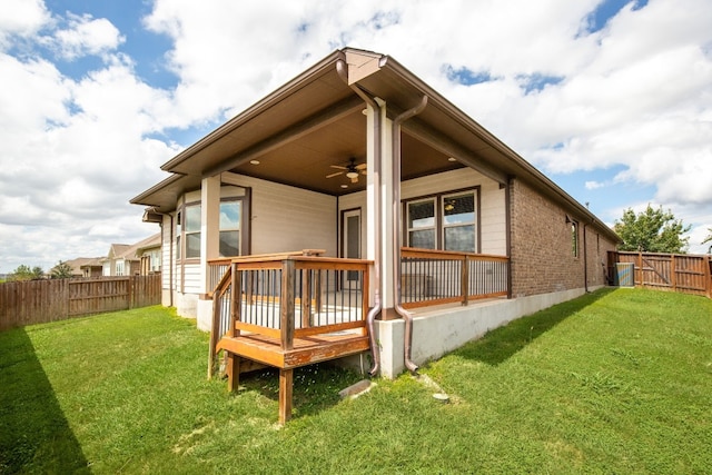 back of property with ceiling fan, a yard, and a deck