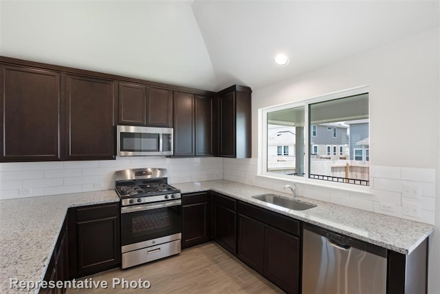 kitchen with appliances with stainless steel finishes, dark brown cabinetry, sink, and tasteful backsplash