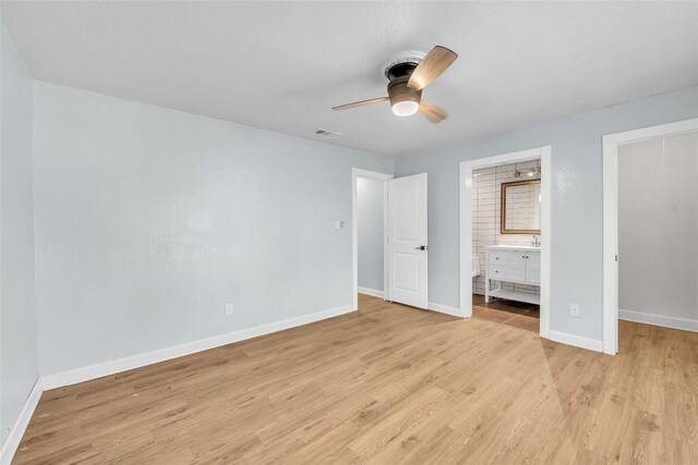 unfurnished bedroom featuring ceiling fan, light wood-type flooring, and ensuite bath