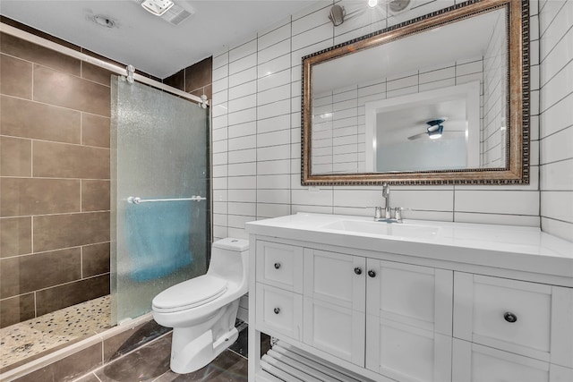 bathroom featuring tile walls, vanity, toilet, and a shower with door