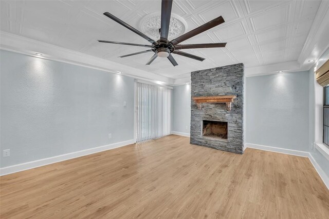 unfurnished living room featuring light hardwood / wood-style flooring, ceiling fan, a fireplace, and crown molding