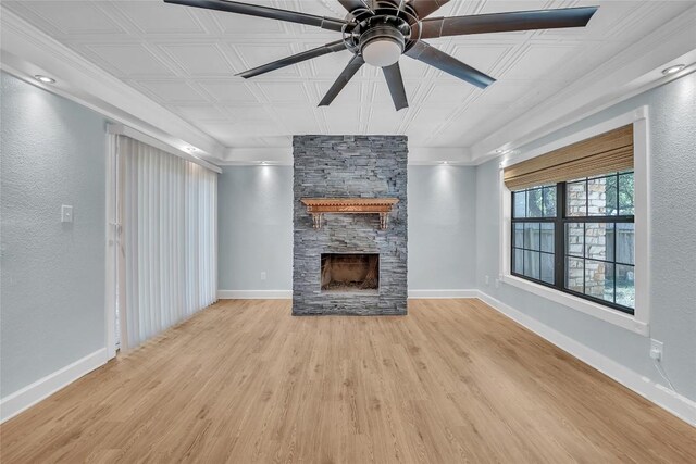 unfurnished living room featuring light wood-type flooring, ceiling fan, a fireplace, and crown molding