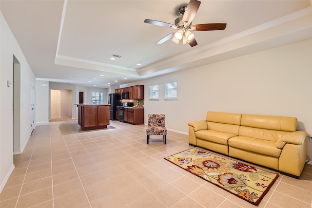 tiled living room with crown molding, a tray ceiling, and ceiling fan