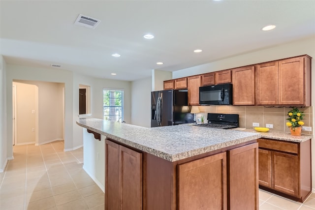 kitchen with a kitchen island, backsplash, light tile patterned floors, and black appliances