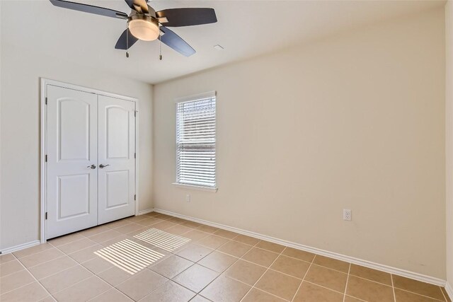 unfurnished bedroom featuring ceiling fan, a closet, and light tile patterned floors