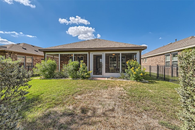 rear view of house featuring a yard and a sunroom