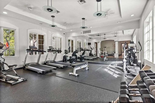 workout area featuring a tray ceiling and ceiling fan