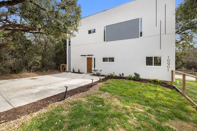 back of house with a lawn and a patio