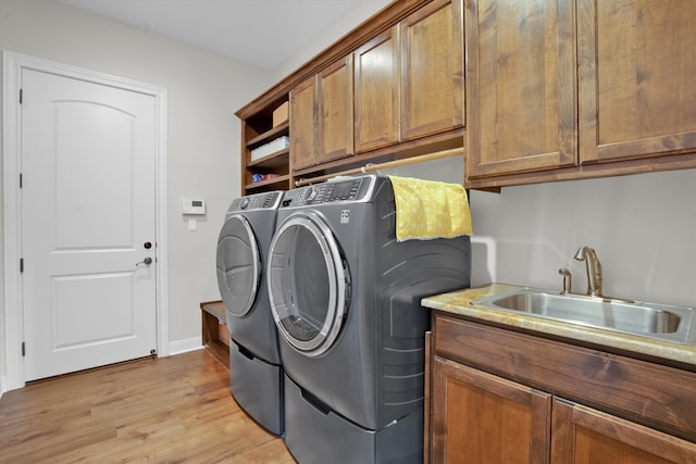 clothes washing area featuring cabinets, light hardwood / wood-style floors, independent washer and dryer, and sink