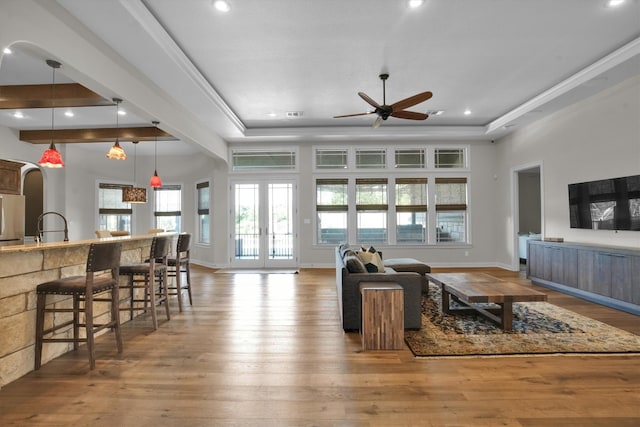 living room featuring a raised ceiling, ceiling fan, french doors, and light hardwood / wood-style flooring