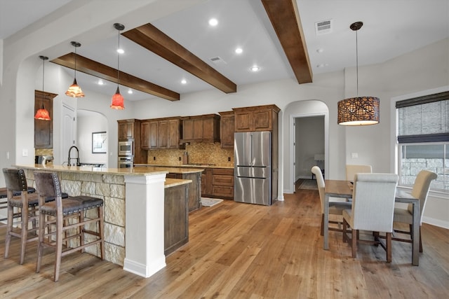 kitchen with pendant lighting, kitchen peninsula, light hardwood / wood-style flooring, stainless steel appliances, and light stone countertops