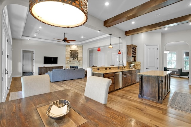 kitchen featuring light hardwood / wood-style flooring, dishwasher, ceiling fan, and a fireplace