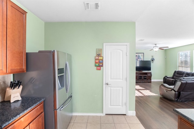 kitchen featuring ceiling fan, light hardwood / wood-style flooring, and dark stone counters