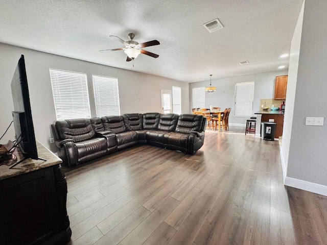 living room with dark wood-style floors, baseboards, visible vents, and a textured ceiling