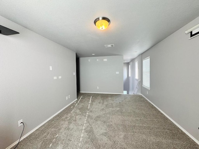 spare room featuring baseboards, visible vents, a textured ceiling, and carpet flooring