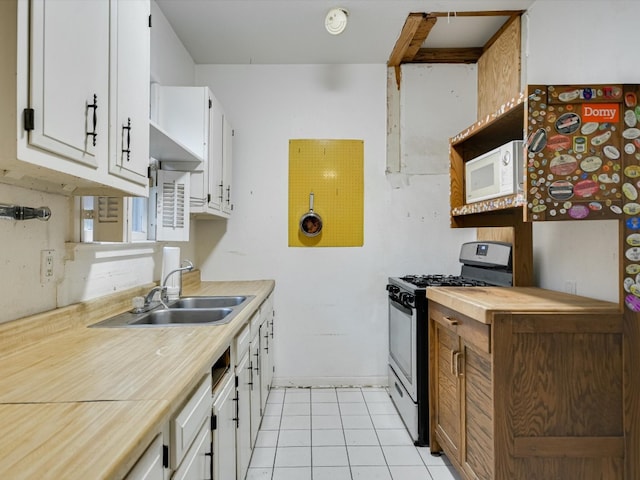 kitchen featuring range with gas stovetop, white cabinetry, light tile patterned floors, and sink