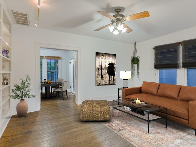 living room featuring ceiling fan, hardwood / wood-style floors, and built in shelves