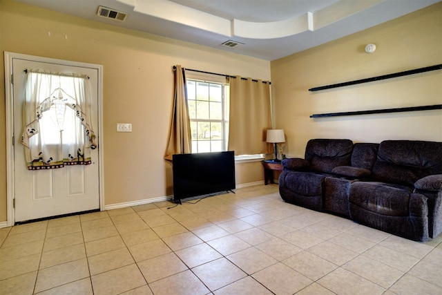 living room with light tile patterned flooring and a raised ceiling