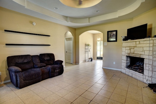 living room featuring light tile patterned flooring, a raised ceiling, and a fireplace