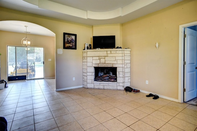 unfurnished living room with an inviting chandelier, a raised ceiling, light tile patterned flooring, and a fireplace