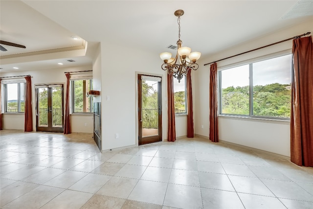 unfurnished room with ceiling fan with notable chandelier and a tray ceiling