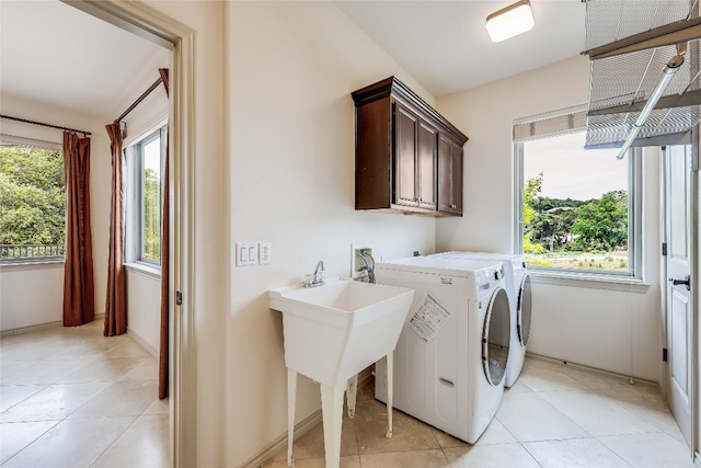 clothes washing area with light tile patterned floors, cabinets, and independent washer and dryer