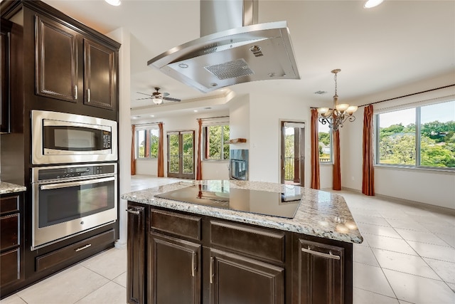 kitchen featuring ceiling fan with notable chandelier, island range hood, appliances with stainless steel finishes, and plenty of natural light