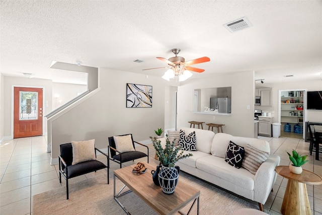 living room with a textured ceiling, light tile patterned flooring, and ceiling fan