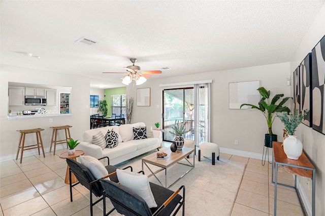 tiled living room with ceiling fan and a textured ceiling