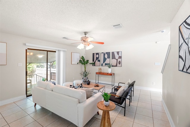 living room featuring a textured ceiling, light tile patterned floors, and ceiling fan