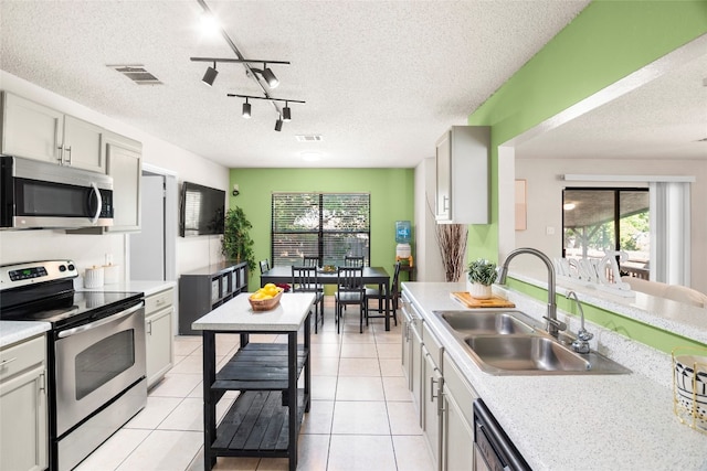 kitchen featuring stainless steel appliances, rail lighting, a textured ceiling, and sink