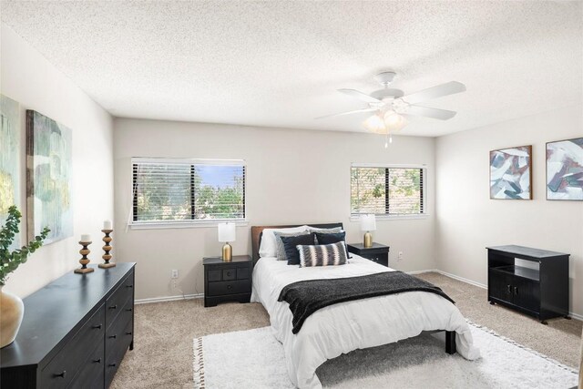 bedroom with ceiling fan, light colored carpet, and a textured ceiling